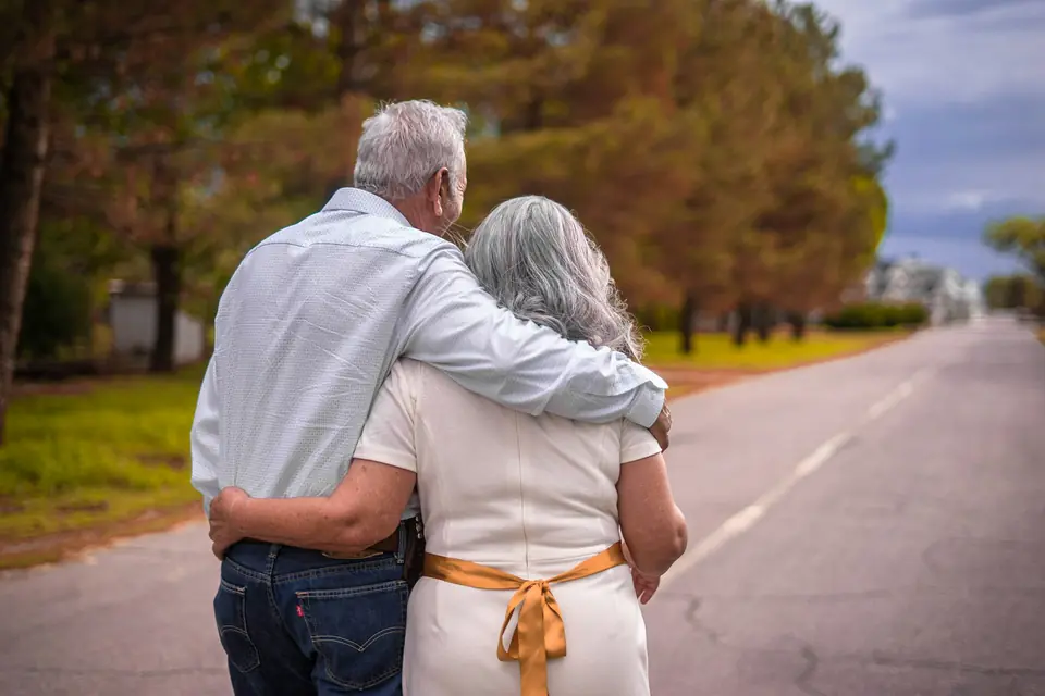 Casal de idosos caminhando abraçado ao ar livre