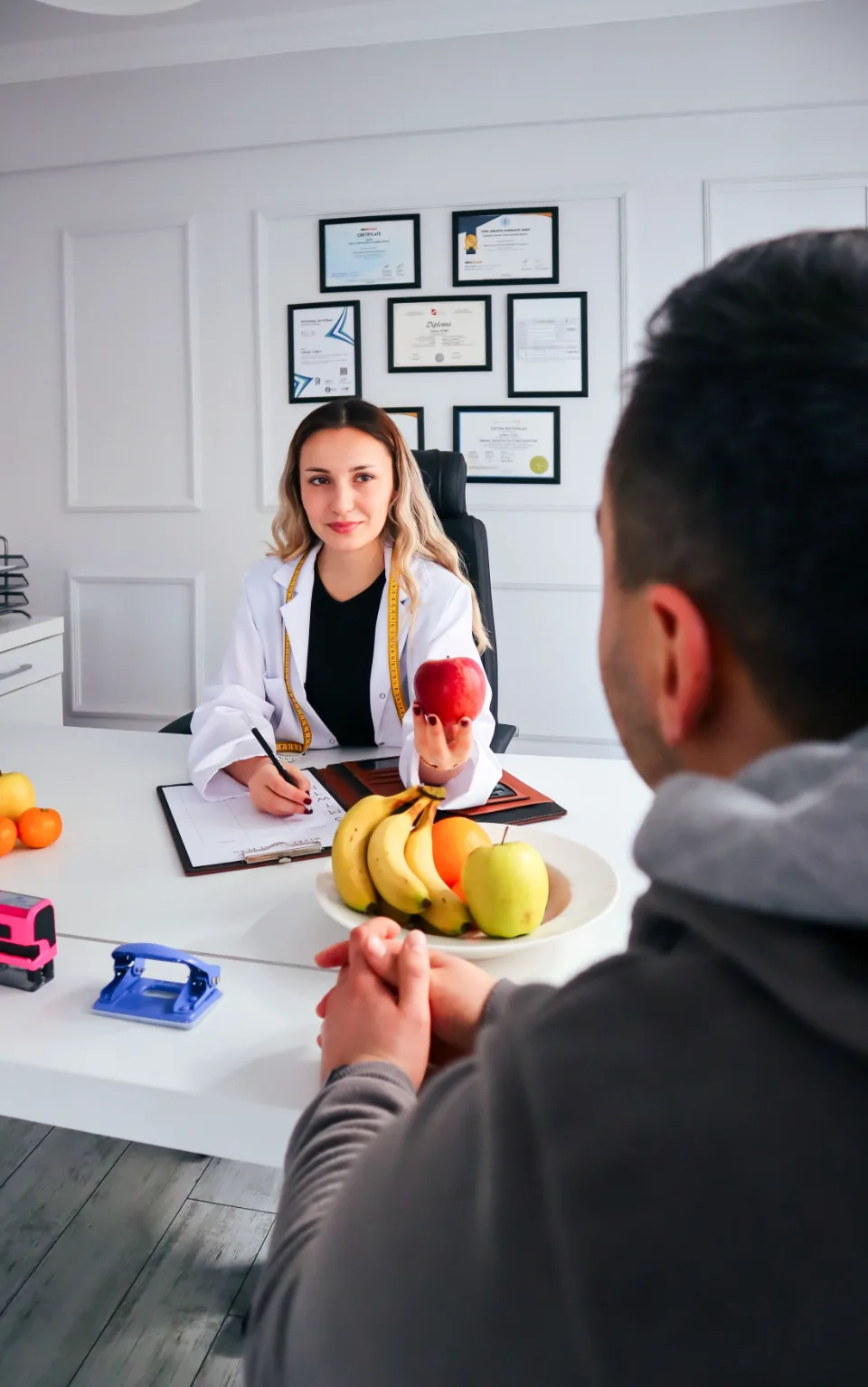 Nutricionista com uma maçã na mão orientando um paciente