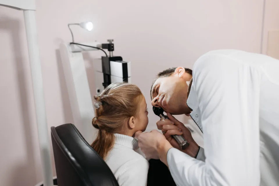 Médico examinando o ouvido de uma menina no consultório