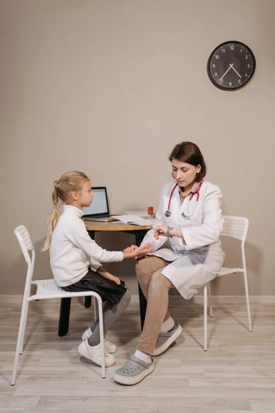 Pediatra atendendo uma menina sentada à mesa do consultório
